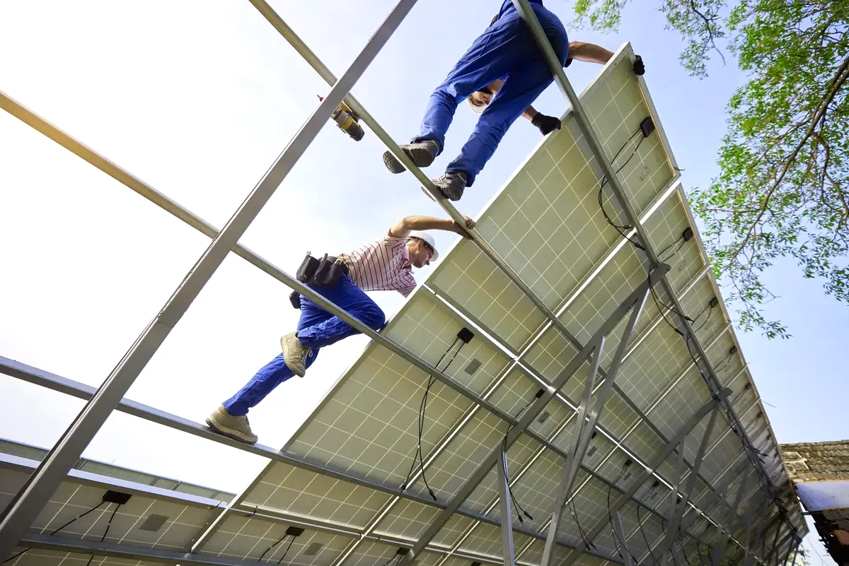 Instaladores trabajando sobre una estructura de paneles solares, instalación de placas solares en Olías del Rey