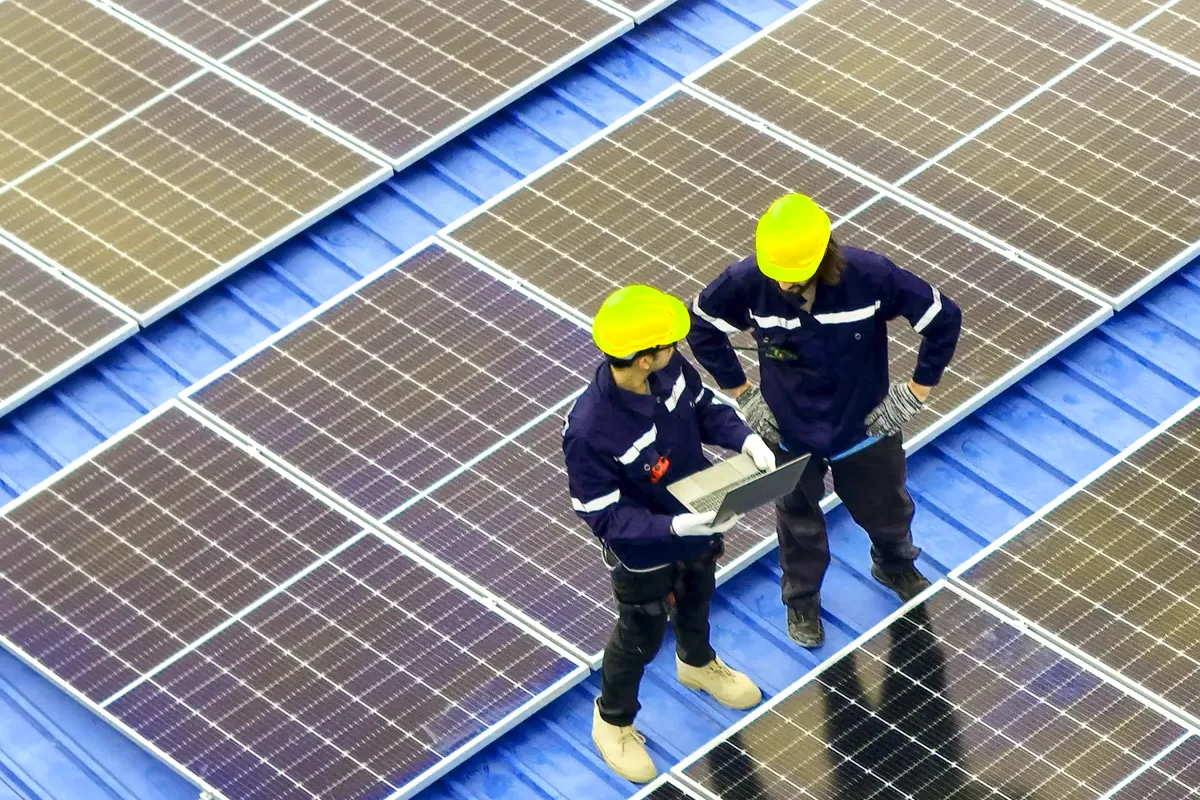 Dos técnicos con casco revisan una cubierta con paneles, criterios para elegir empresa de placas solares en Toledo