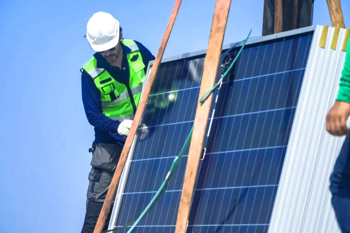 Instalador con casco ajustando un panel solar en una vivienda, paneles solares en Argés cerca de Toledo